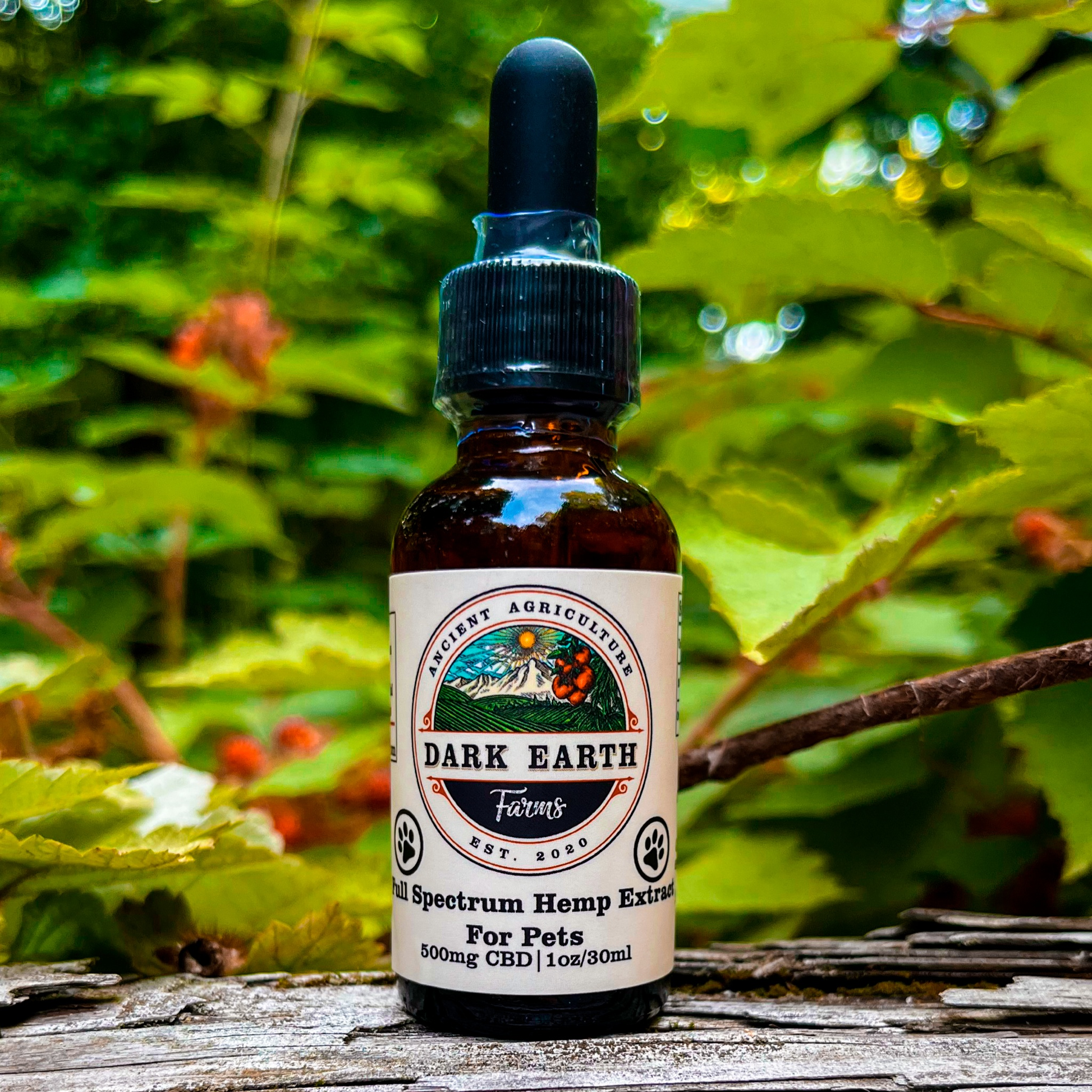 An image of a small bottle labeled Dark Earth Farms Full Spectrum Hemp Extract for Pets, featuring a green and yellow label with the brand name and product information. The bottle contains 500mg of CBD oil with terpenes and cannabinoids, specifically designed for pets to help alleviate pain, anxiety, and improve sleep. The bottle is placed on a wooden surface, surrounded by hemp leaves and a small dropper next to it, ready for use.